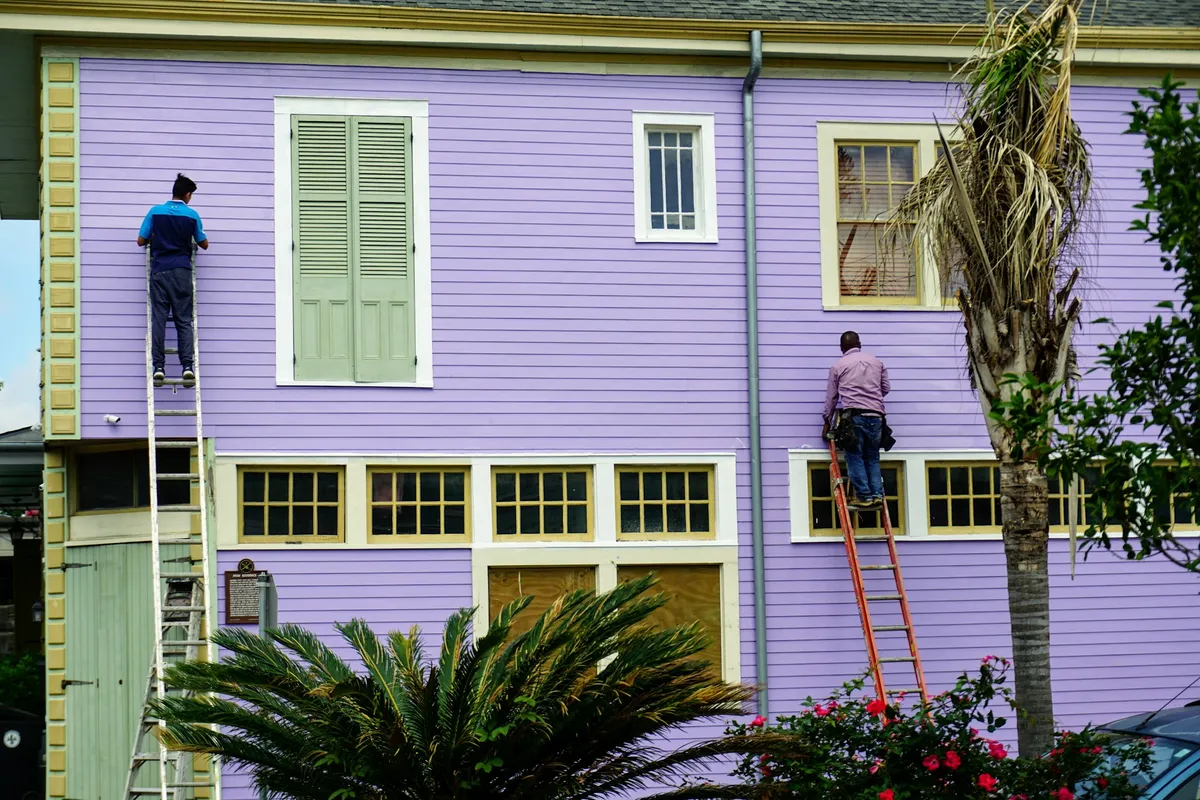 Peintres sur des échelles, au travail sur une façade en bois